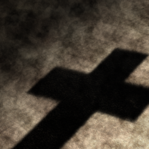 Into The Wilderness Graphics. Shadow of a cross seen on the barren desert ground.
