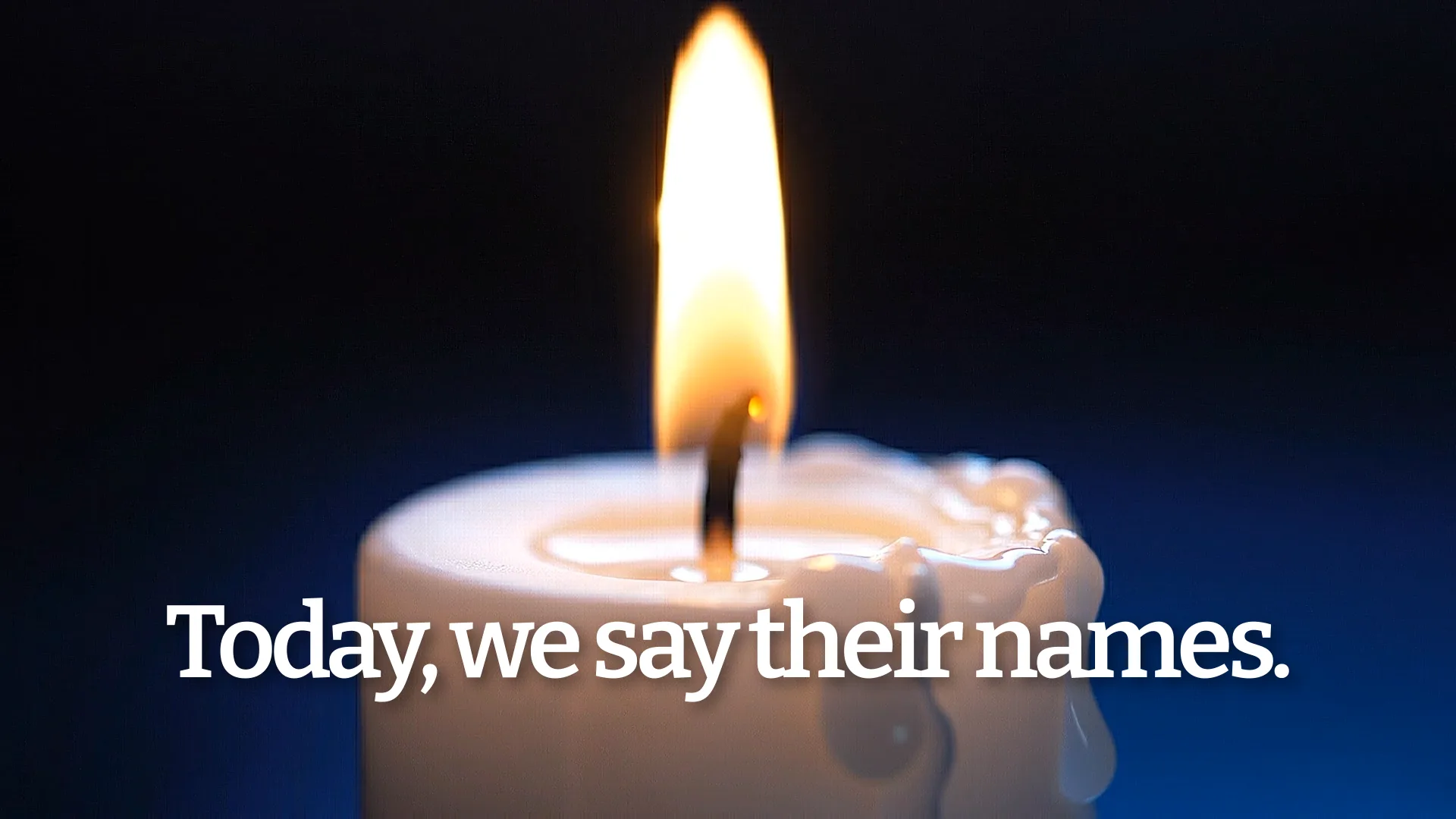 Lit candle with bright flame against dark blue background for All Saints Day remembrance