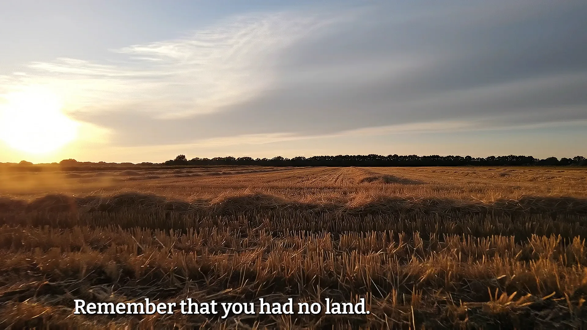 Harvested grain field at sunset with text "Remember that you had no land